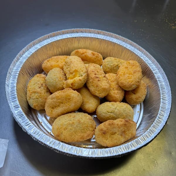 A foil container filled with golden-brown, breaded jalapeño poppers from Big T's Pizza.
