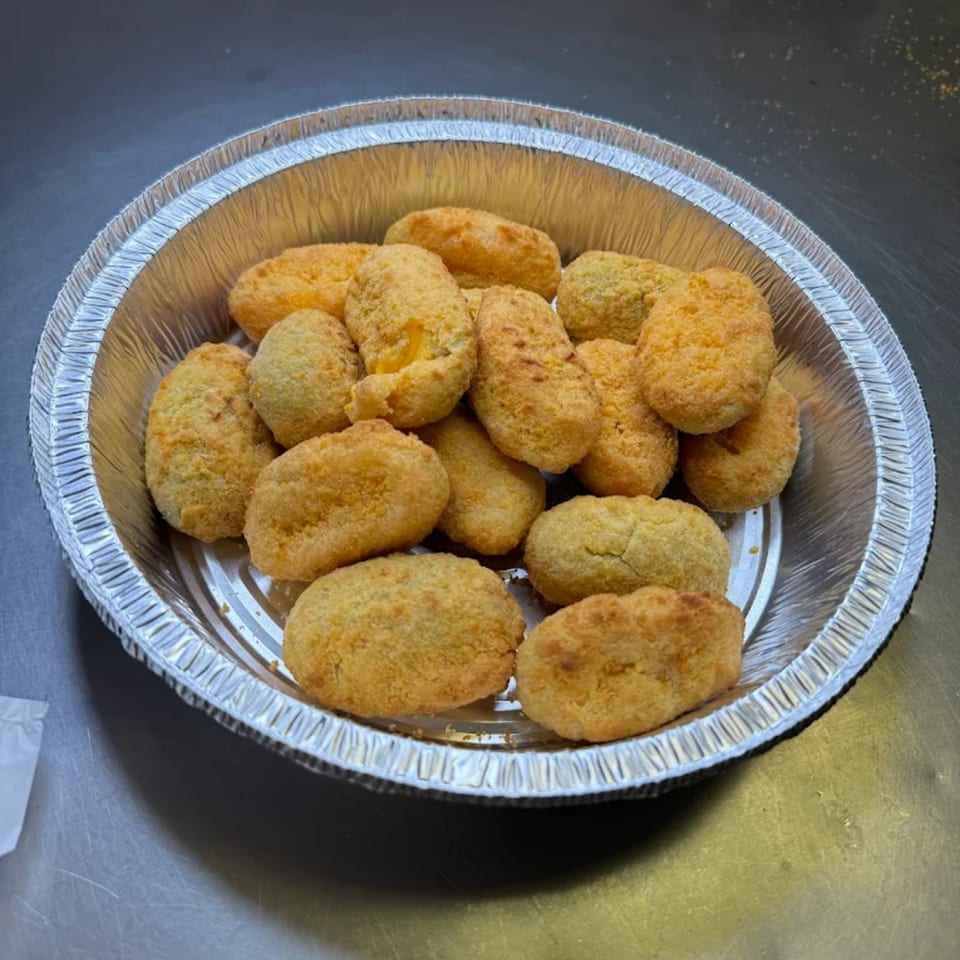 Golden-brown Big T's Pizza jalapeño poppers, breaded and fried, served in a round aluminum takeout container.