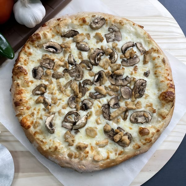 Big T's Pizza white pizza with mushrooms and chicken on a wooden peel.